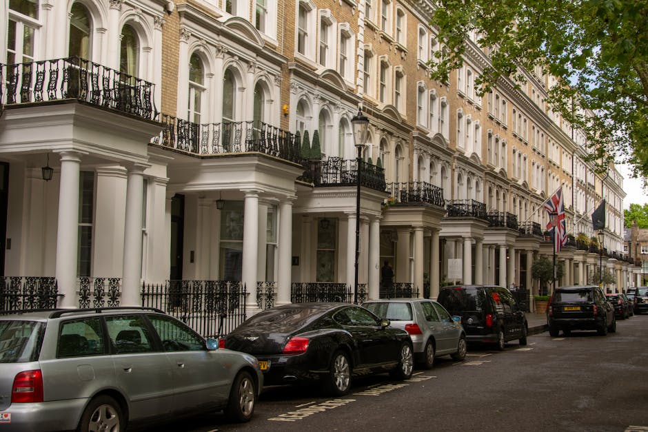 Photograph of a historic red-brick residential building in Belgravia with multiple floors featuring white-framed sash windows and ornate architectural details. The building has a decorative white balu