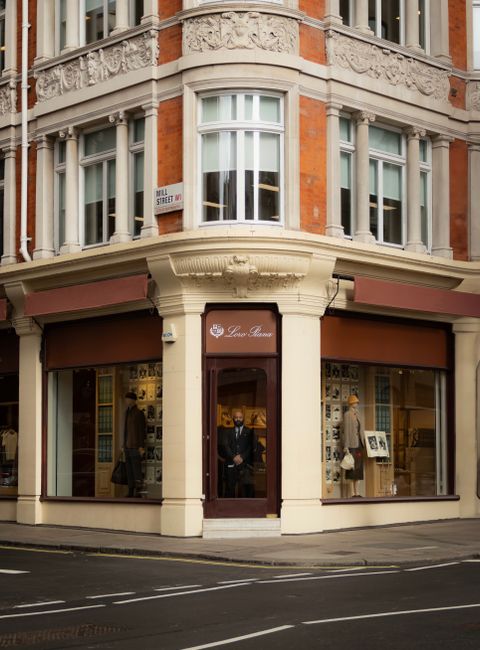 Exterior view of a historic red brick building with multiple floors, featuring white-framed sash windows and decorative architectural details. The ground floor has arched doorways and windows, with a 